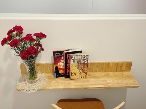 a shelf with a vase of flowers and books at Yen Minh Resthouse in Ho Chi Minh City