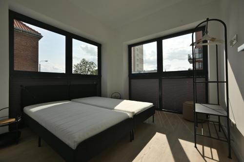 a bedroom with a bed and two large windows at Dluga Grobla 6 Apartments Oldtown in Gdańsk