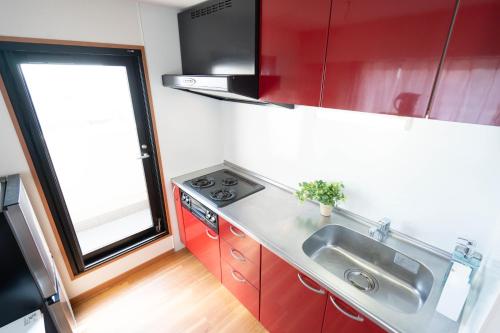 a kitchen with red cabinets and a sink and a window at JR住吉駅徒歩30秒 眺望抜群の貸切ペントハウスLn30 in Kobe