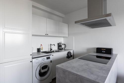 a white kitchen with a washing machine and a sink at Dvouložnicový apartmán Sluníčko in Zásada