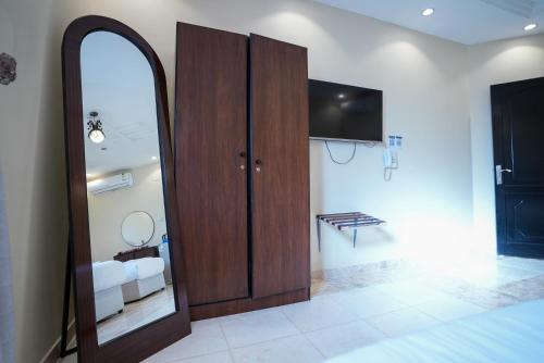 a bedroom with a mirror and a tv on a wall at ركن صحاري للشقق المخدومة العليا Rukn Sahari for Served Apartments in Tabuk