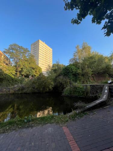 a park with a pond and a tall building at Stylish 1 Bed Apartment - Birmingham city Centre in Birmingham