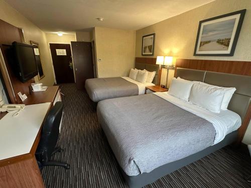 a hotel room with two beds and a flat screen tv at Quality Inn near Toms River Corporate Park in Manchester Township