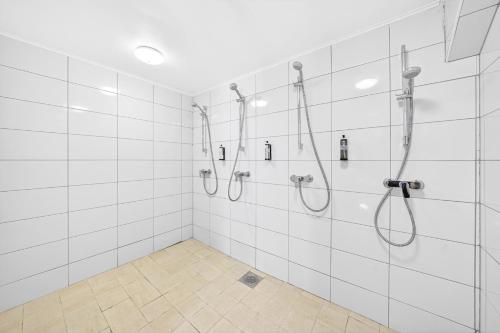 a bathroom with white tiled walls and showers at Angaar - Tallinn Airport in Tallinn