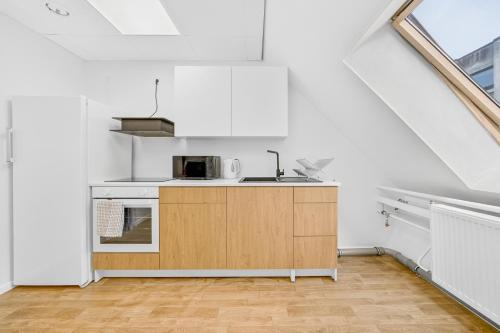 a white kitchen with a sink and a microwave at Angaar - Tallinn Airport in Tallinn