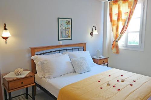 a bedroom with a bed with white sheets and a window at Maroussa Studios in Agia Anna Naxos