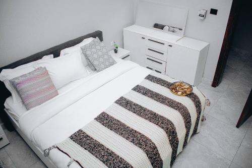 a bedroom with a white bed with a black and white blanket at Care Appartement in Kinshasa