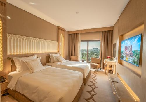 a hotel room with two beds and a television at World Heart Hotel in Baghdad