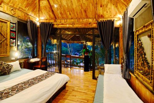 two beds in a room with a person standing in the background at Thái Tâm homestay in Mai Chau