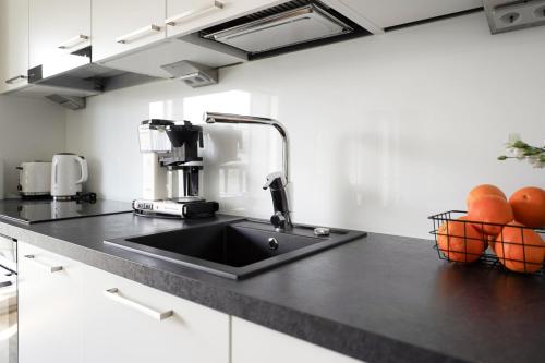 a kitchen with a sink and oranges on the counter at Mall of Tripla apartments by Come in! in Helsinki