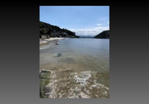 a body of water with a group of people on a beach at Pousada Prainha do Horizonte in São Vicente