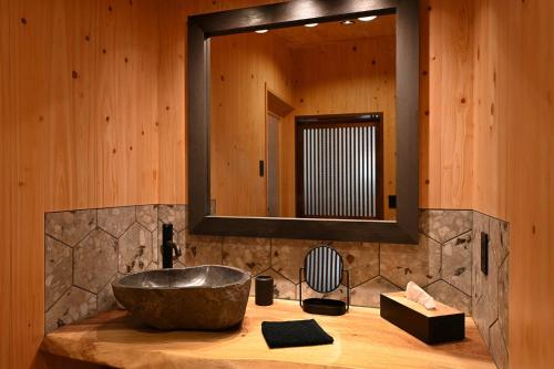 a bathroom with a stone sink and a mirror at Koya Miyama in Nantan city