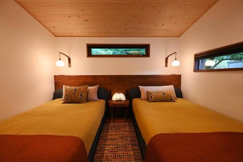 two beds in a small room with two windows at Koya Miyama in Nantan city