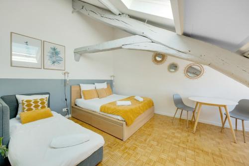 ベルサイユにあるLes Mansardes du Roi - Tout proche châteauのベッドルーム1室(ベッド2台、テーブル、テーブル付)