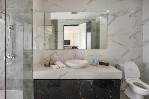 a bathroom with a sink and a toilet and a mirror at The Hill Ocean View Villa - Jimbaran Bali in Uluwatu