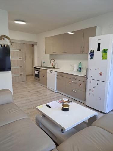 a kitchen with a white refrigerator and a table at Moderní apartmán s balkonem v srdci Pardubic in Pardubice