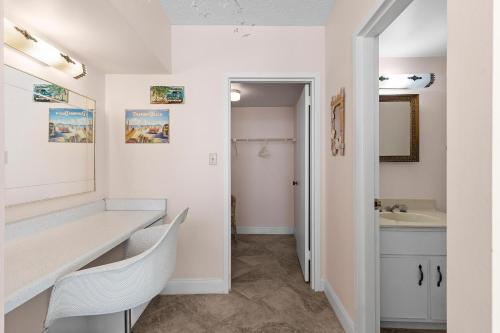 a bathroom with a sink and a vanity with a mirror at Golden Arms 803 in New Smyrna Beach