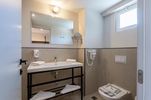a bathroom with a sink and a mirror and a toilet at Smy Kos Beach & Splash in Mastichari
