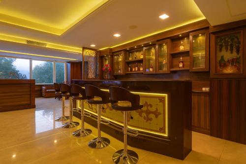 a bar with a bunch of stools in a room at The Four Season Dharamshala # Centrally Heated & Air Cooled # Scenic Mountain View # Big Parking # Near Market # Top Rated # Most Awarded # Premium Rooms # Bar # Terrace # Lift # Property Of The Year##BY ROYAL GROUP# in Dharamshala