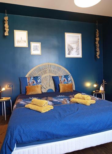 a blue bedroom with a large blue bed with yellow pillows at La Cabane des Mouts- Piscine -Clim in Fleury