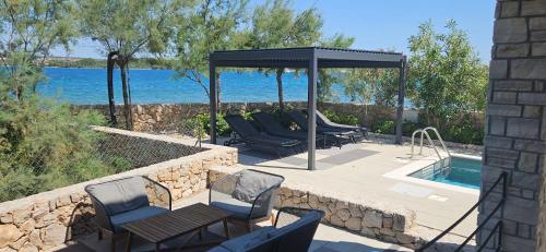 a patio with chairs and a gazebo next to a pool at Royal House 1 in Pašman