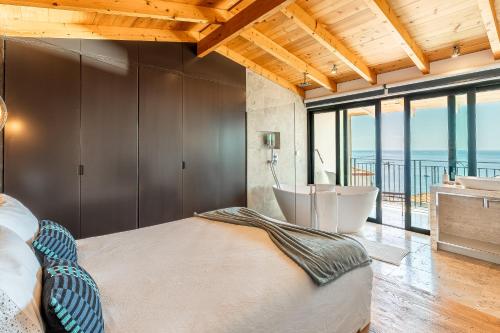 a bedroom with a large bed and a bathroom with a tub at Port and Stone Villa in Funchal