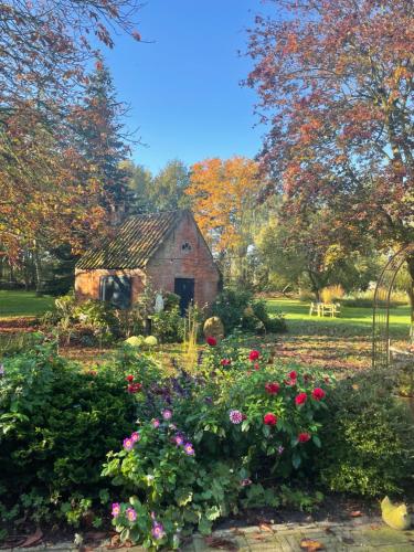 an old barn in the middle of a garden with flowers at d'oude hoeve in Rijsbergen