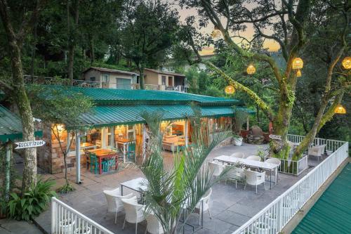 un patio con tavoli e sedie e un edificio di Echor Malusara Lakeview Retreat Bhimtal a Bhimtal