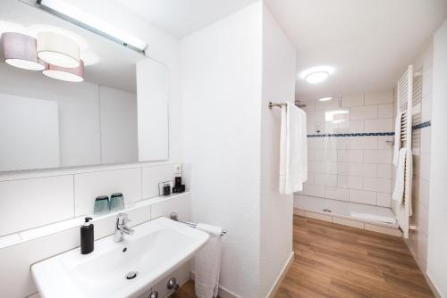 a white bathroom with a sink and a mirror at Mäsers Allgäuherz in Wiggensbach