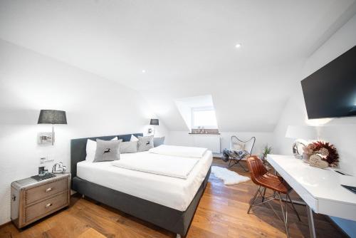 a white bedroom with a bed and a desk at Mäsers Allgäuherz in Wiggensbach