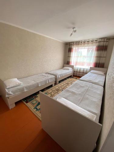a room with four beds and a window at Aiza Apartments in Naryn