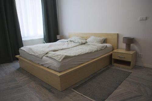 a bedroom with a bed with a night stand and a window at Artovna České Budějovice in České Budějovice