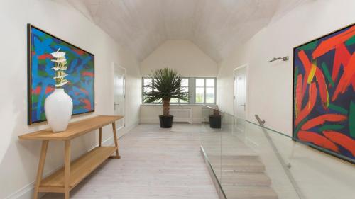 a hallway with paintings on the wall and a vase on a table at Posiadłość Wiejska i Ogrody Acqua di Rosa in Zameczek