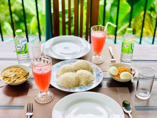 a wooden table with plates of food and drinks at Liana Guest House Ella in Ella