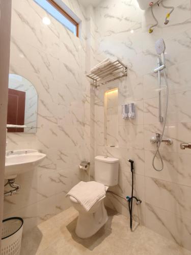 a white bathroom with a toilet and a sink at Tentram guesthouse in Waikabubak