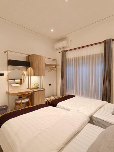 a hotel room with two beds and a desk at Tentram guesthouse in Waikabubak