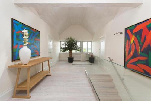 a hallway with two paintings on the wall and a vase on a table at Posiadłość Wiejska i Ogrody Acqua di Rosa in Zameczek