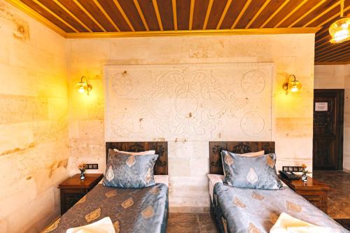 two beds in a room with yellow walls at Nest Cappadocia Hotel in Uchisar
