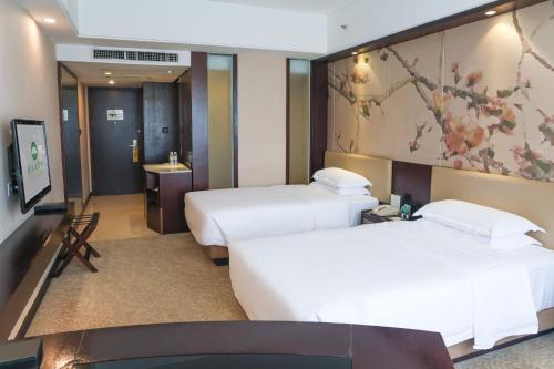 a hotel room with two beds and a painting on the wall at Guangdong Yingbin Hotel-Free Canton Fair Shuttle Bus in Guangzhou