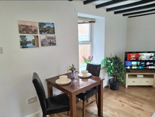 a dining room with a table and chairs and a tv at Chantry Place Morpeth House in Morpeth