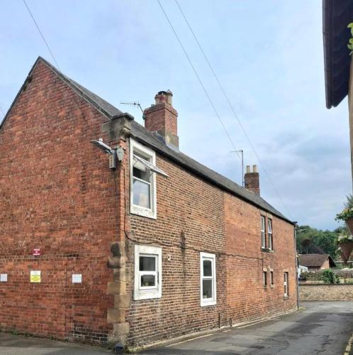 an old brick building with two windows on a street at Chantry Place Morpeth House in Morpeth