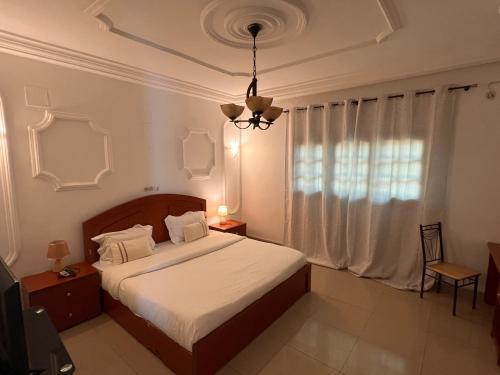 a bedroom with a bed and a chandelier at Hotel La Roche in Brazzaville