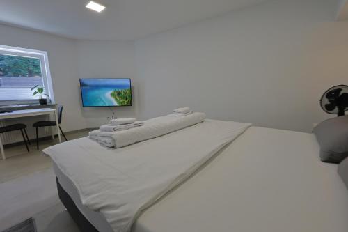 a white bedroom with a bed and a desk at Ausblick residence in Badenweiler