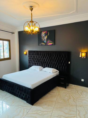 a bedroom with a large bed with a black headboard at Résidence o-calme in Yaoundé