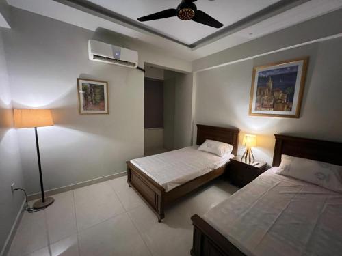 une chambre avec deux lits et un ventilateur de plafond dans l'établissement Prestige comforts, à Karachi