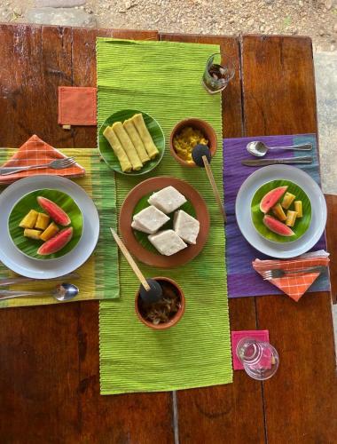 a table with plates of food on a wooden table at Sahana Retreat in Buttala