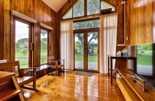a living room with wooden walls and large windows at Nan Homey Space น่านโฮมมี่สเปซ in Nan
