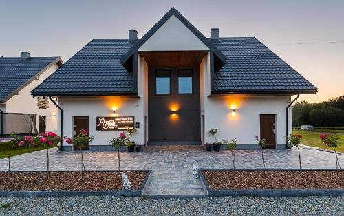 a white house with a black roof at Solina Bóbrka Apartamenty PanDamazy 530-487-636z widokiem na kamieniołom i Zalew Myczkowiecki in Solina