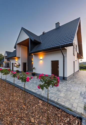 a house with pink flowers in front of it at Solina Bóbrka Apartamenty PanDamazy 530-487-636z widokiem na kamieniołom i Zalew Myczkowiecki in Solina