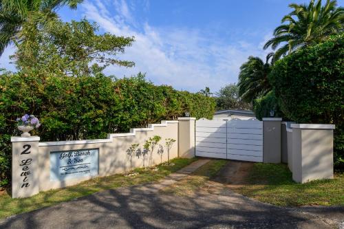 a white fence with a gate and trees at Golf Beach and Sea in Southbroom